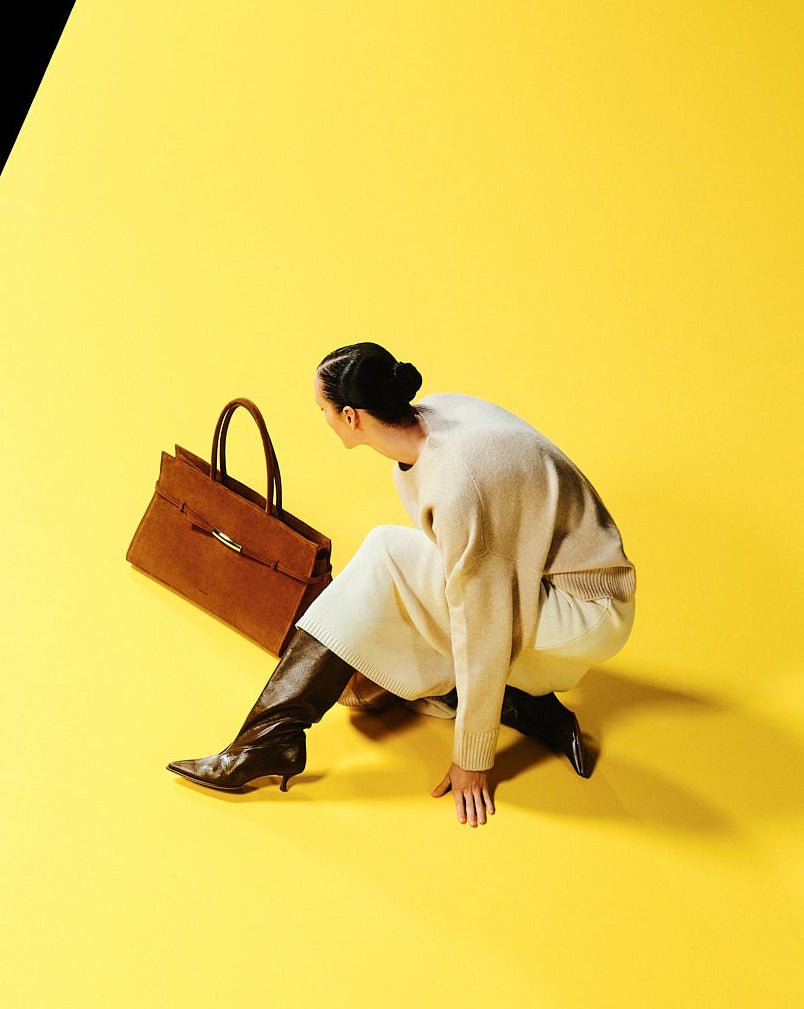 Person sitting on a yellow floor with a Poelle's Object 03 brown handbag