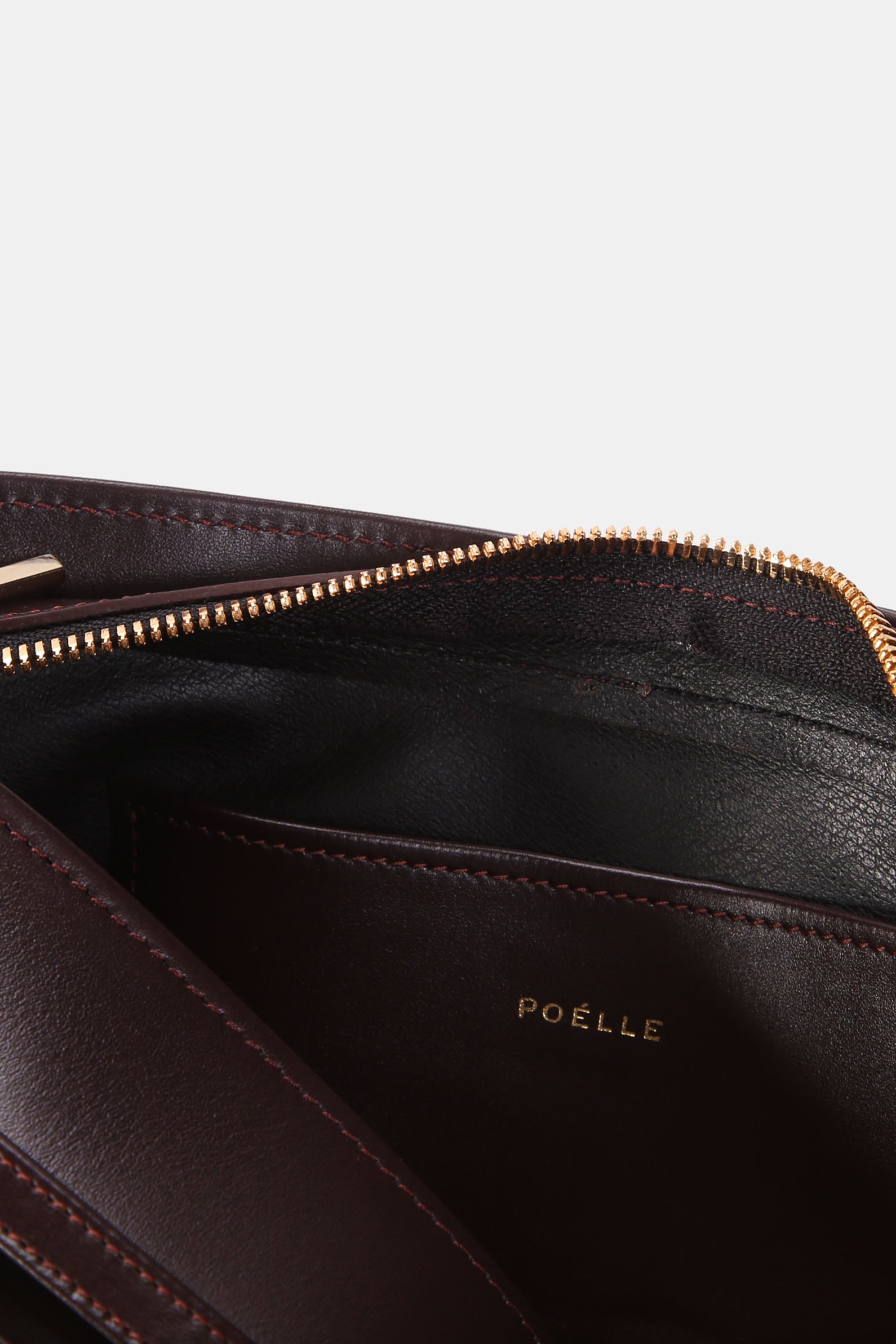 Close-up of Poelle Atelier brown leather shoulder bag interior with gold zipper and logo detail