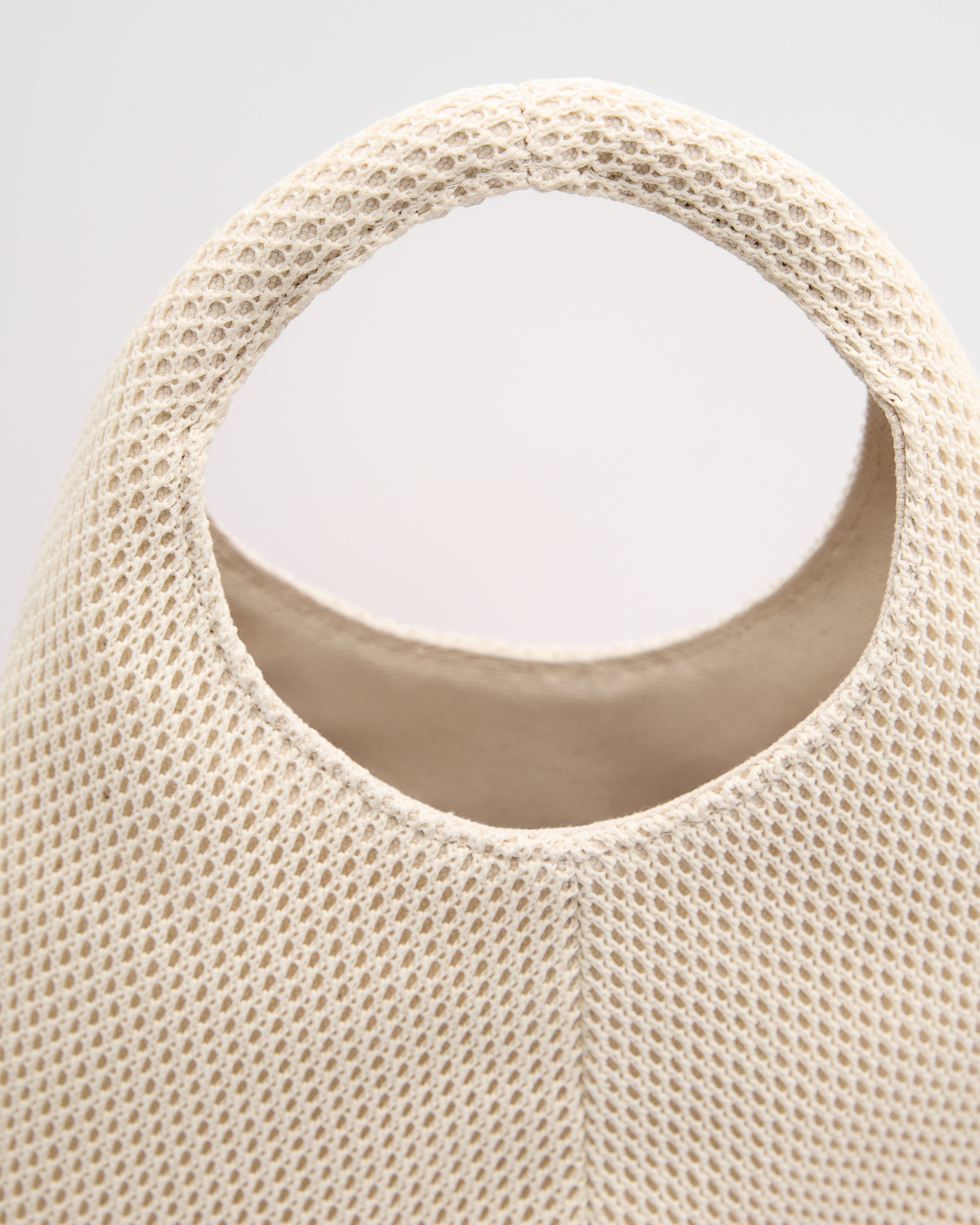 Close-up of Poelle Atelier luxury minimalist summer bag in textured beige fabric with round handle