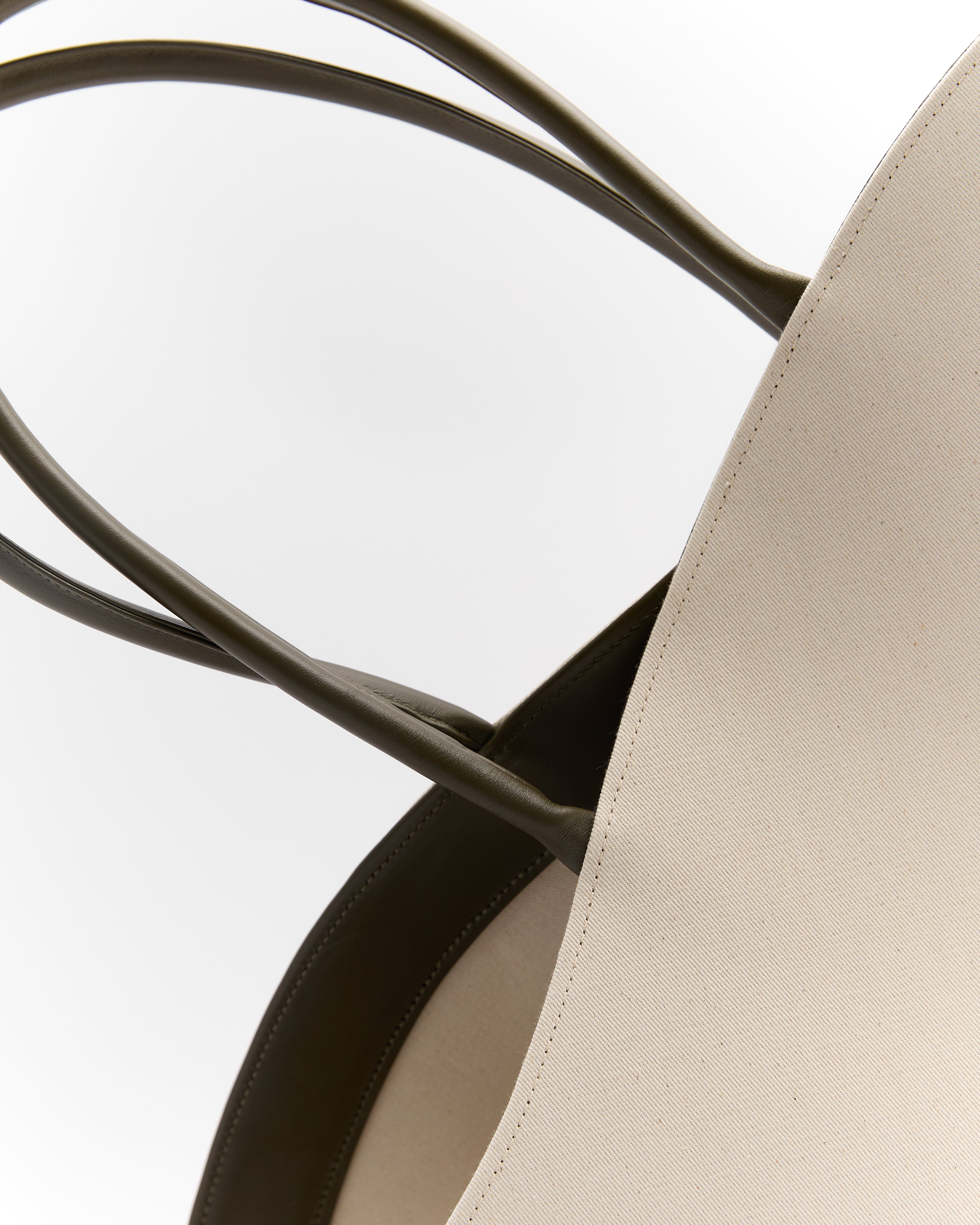 Close-up of luxury summer leather bag handles and beige fabric body by Poelle Atelier