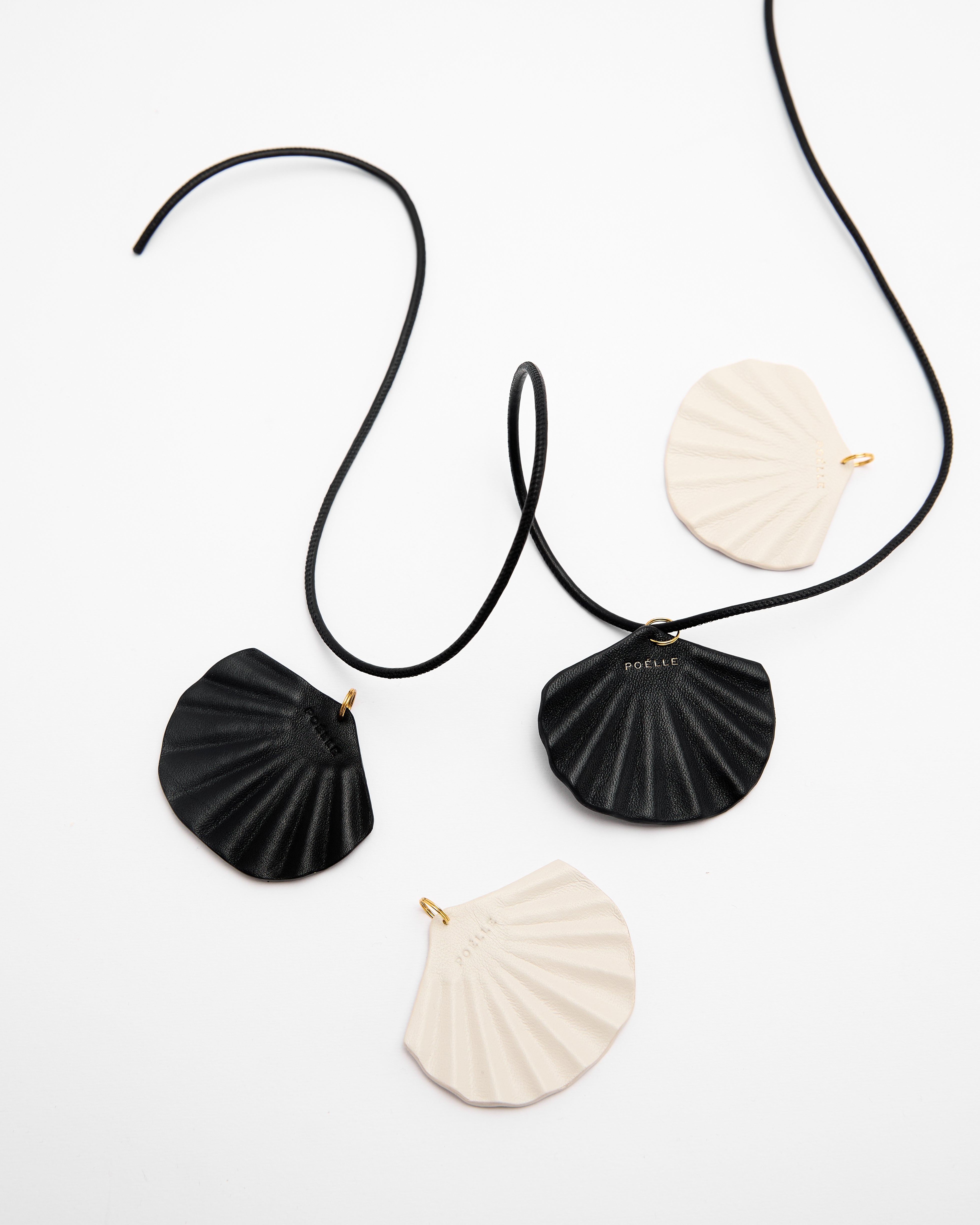 Minimalist summer leather necklace by Poelle Atelier with black and white shell-shaped pendants on black cord