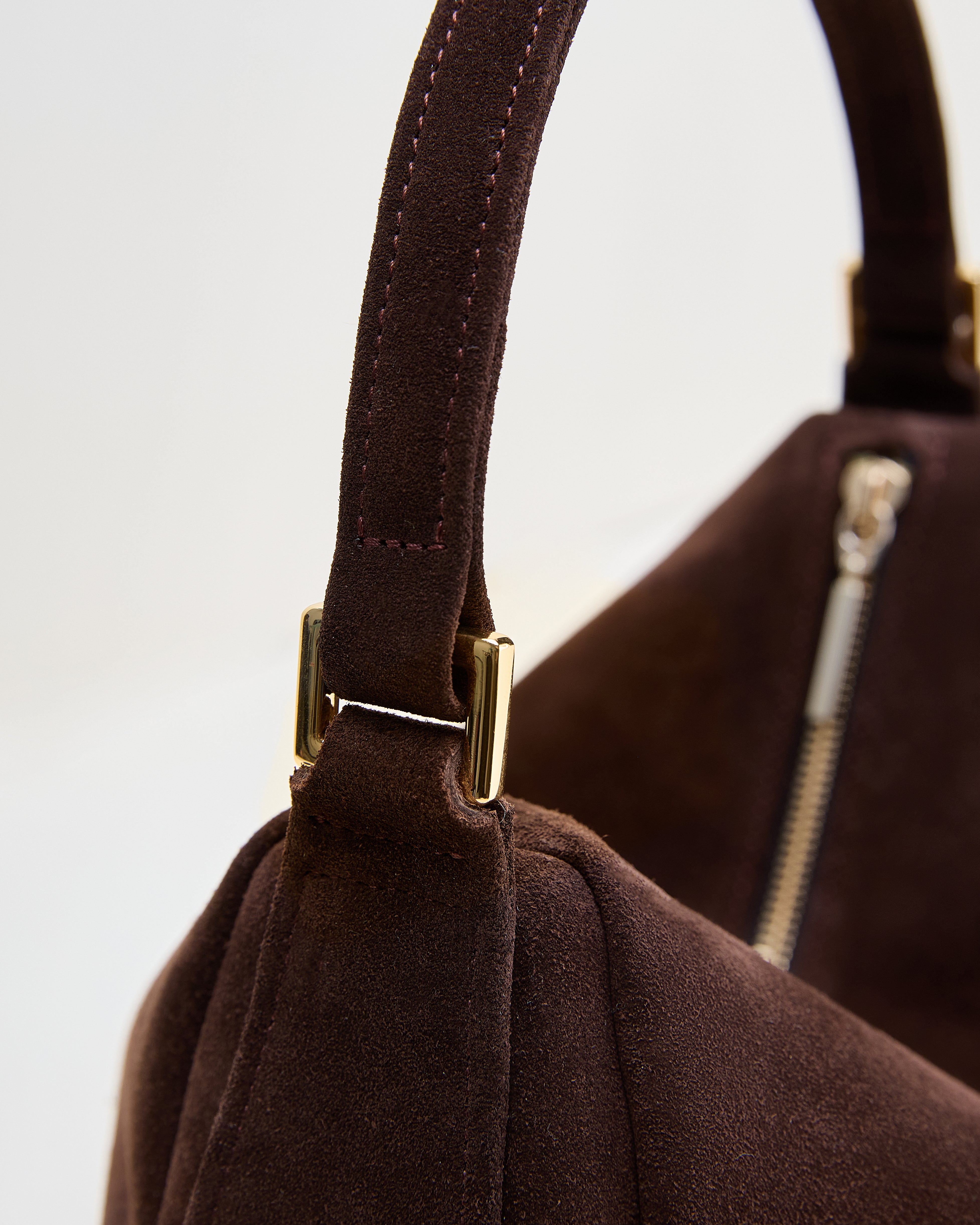 Close-up of Poelle Atelier brown leather bag minimalist with suede texture and gold hardware zipper detail