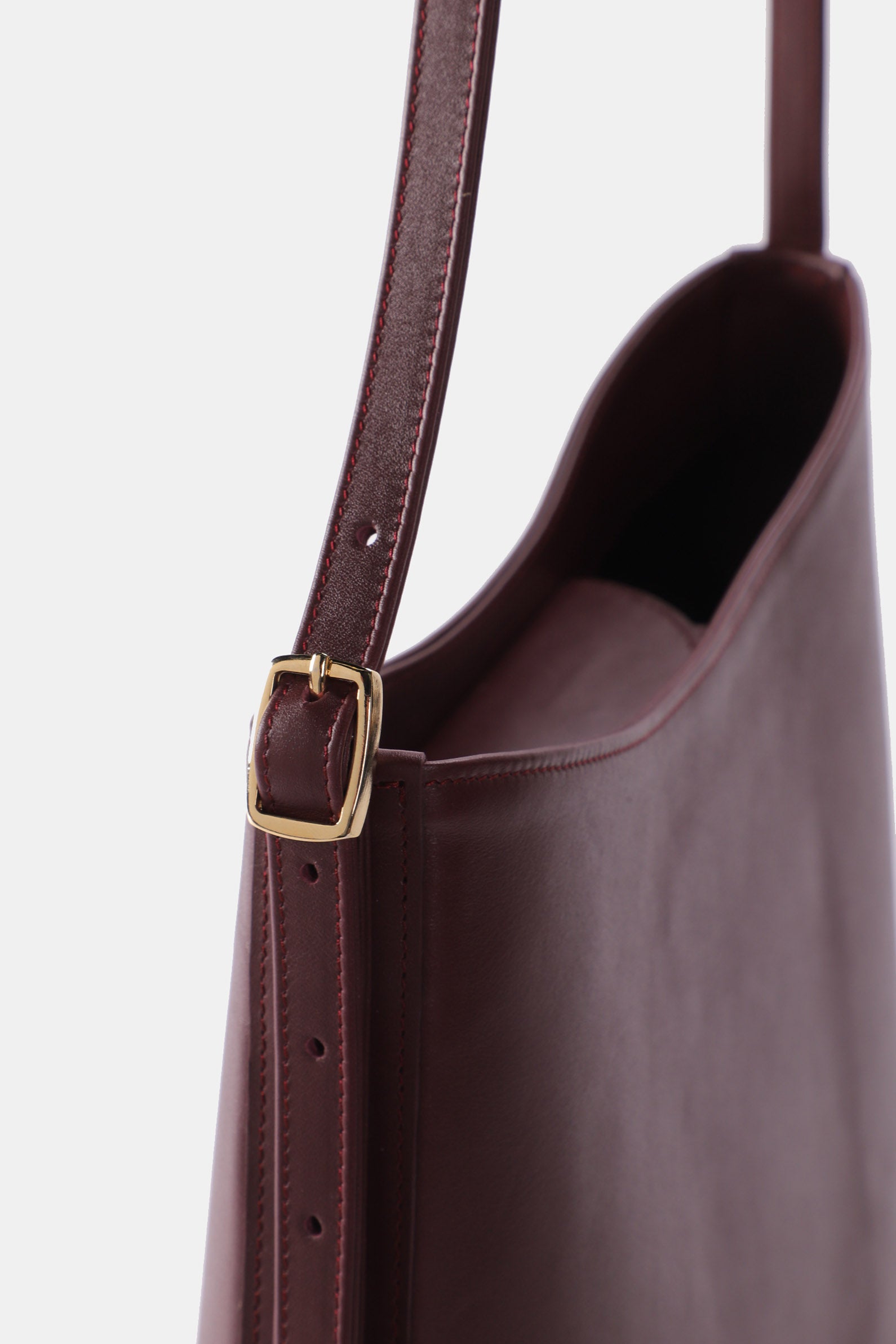 Poelle Atelier luxury minimalist sculptural bag in rich brown leather with adjustable strap and gold buckle